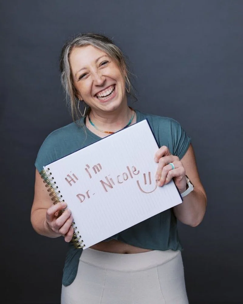 Dr. Nicole Woodard holding a notebook introducing herself